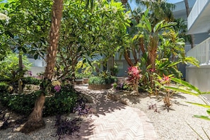 Ein Garten mit einem Ziegelweg, verschiedenen Pflanzen und einem Gebäude im Hintergrund.
