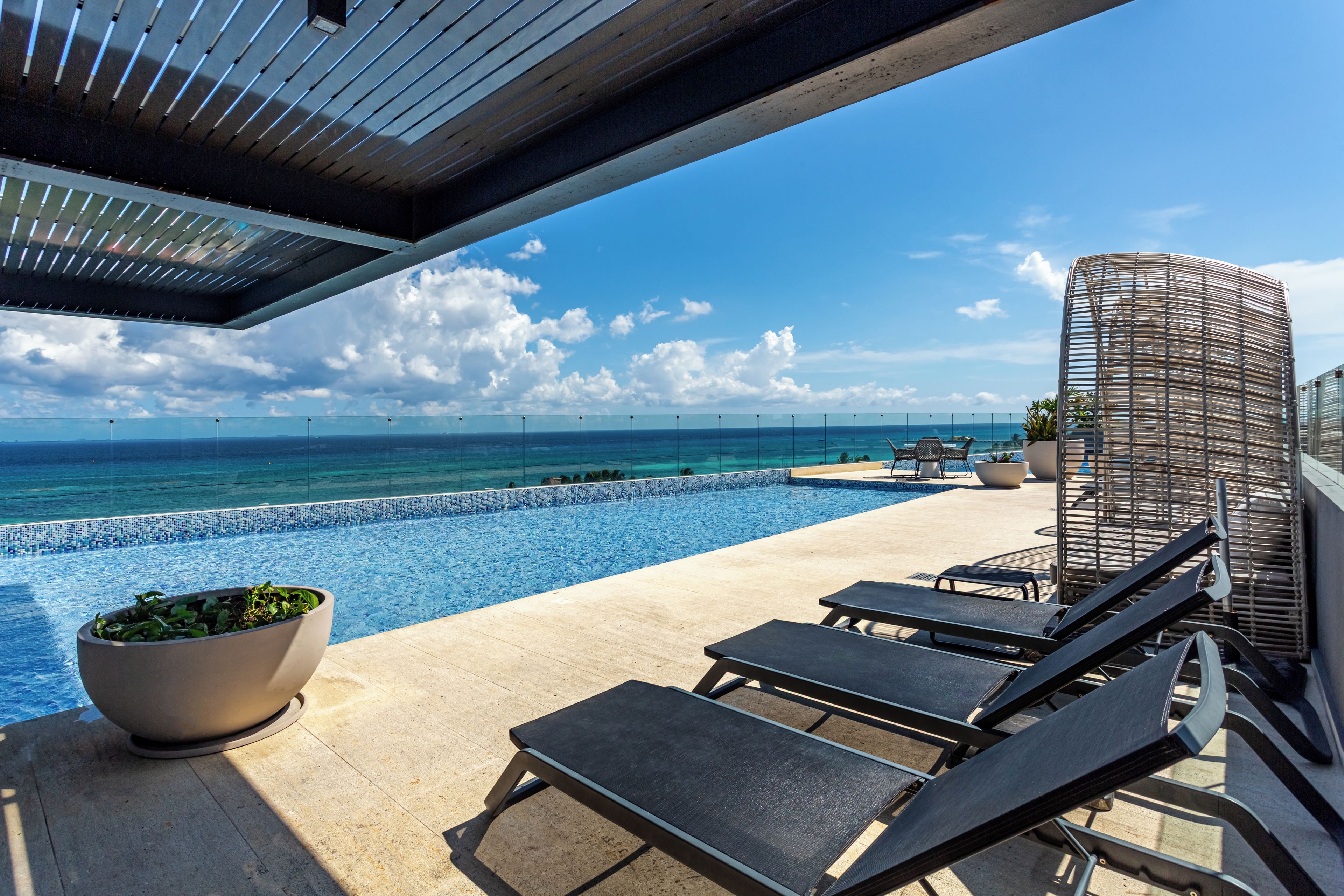 A poolside area with lounge chairs and a view of the ocean.