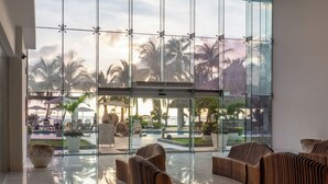 Eine moderne Lobby mit einer Glaswand, Holzmöbeln und einem Poolbereich, der durch die Glaswand sichtbar ist.