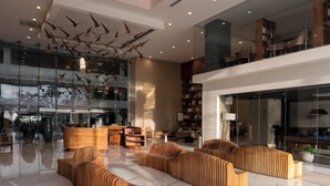 Eine moderne Lobby mit Holzmöbeln, einer Glaswand und einer Decke mit hängenden Leuchten.