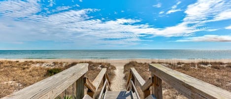 A wooden boardwalk leading to a beach with clear skies.
