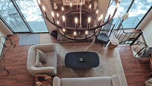 A modern living room with a circular chandelier, two sofas, a coffee table, and a view through a glass door. - Private homes Beech Mountain! (Beech Mountain)