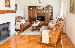 A living room with a fireplace, wooden furniture, a television, and a chandelier. - Gorgeous home in Buzim (Buzim)
