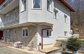A two-story house with a stone facade, a balcony, and a small outdoor seating area with chairs and a table. - Gorgeous home in Buzim (Buzim)