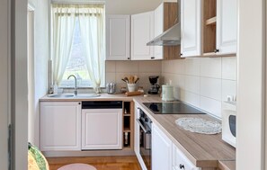 A modern kitchen with white cabinetry, a dishwasher, an oven, and a coffee maker. - Gorgeous home in Buzim (Buzim)