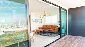 Een moderne woonkamer met een bank, salontafel en uitzicht door een glazen deur.