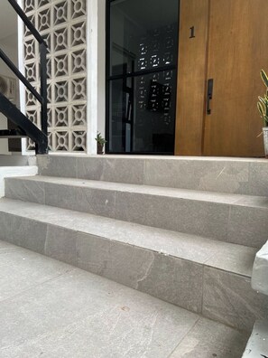A set of stone steps leading to a door with a glass panel and a wooden door frame. - Private Pool Apartment by the Malecón (Mazatlan)