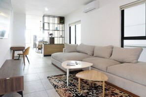 A modern living room with a sofa, a coffee table, a dining table, and a chair. - Private Pool Apartment by the Malecón (Mazatlan)