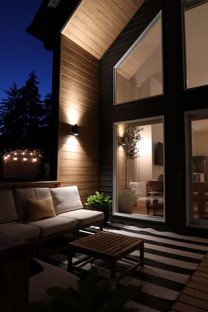 A modern house with a wooden exterior, a black and white striped rug, a sofa, and a table.