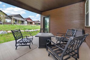 Une terrasse extérieure avec une table et des chaises, un espace abrité et une vue sur les maisons au loin.