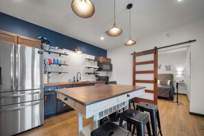A modern kitchen with a central island, stainless steel appliances, and pendant lighting. - The Oasis at Stonebriar (Lindale)