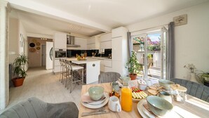 Una cocina moderna con armarios blancos, una isla central y taburetes de bar.