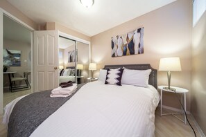 A neatly made bed with pillows, a bedside lamp, and a painting on the wall. - Cozy 2BR Suite In Lewis Estates Golf Course By Henday/Whitemud-Long Stay Suite! (Edmonton)