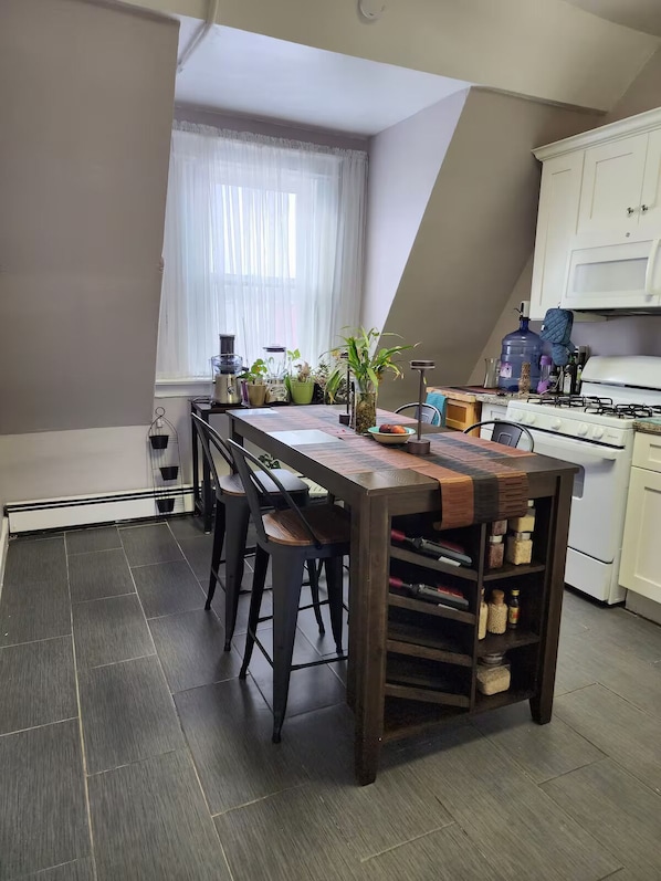 A kitchen with a long island, bar stools, a stove, and a refrigerator. - Newark Furnished Apartment for World Cup (Newark)