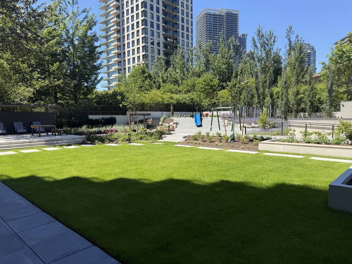 A landscaped courtyard with a grassy area, seating, and a playground.
