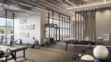 A modern gym with exercise equipment, a wall with 'THE HEALTH CLUB' text, and large windows.