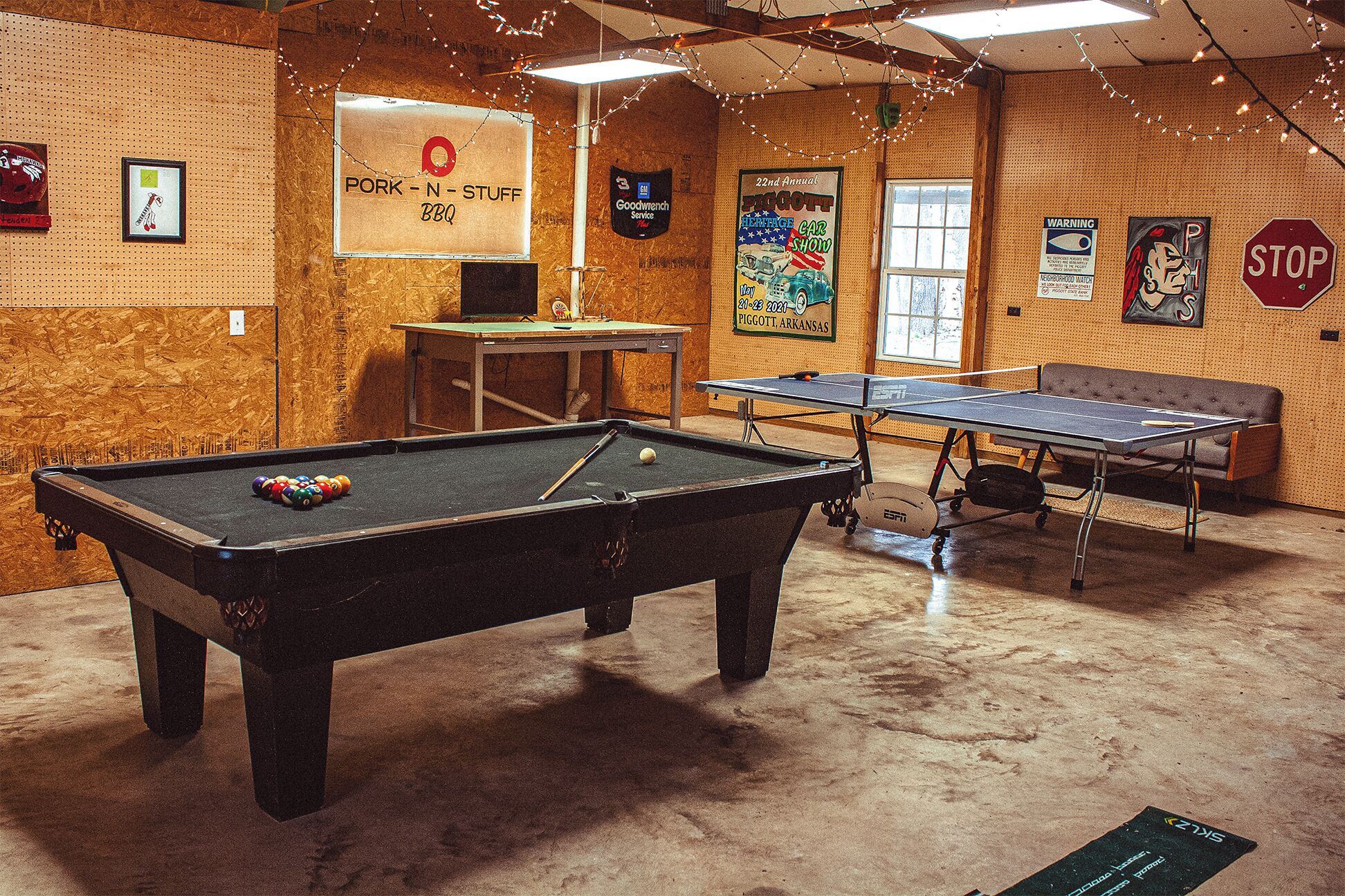 A recreational room with a pool table, ping pong table, and a sign for a BBQ event.
