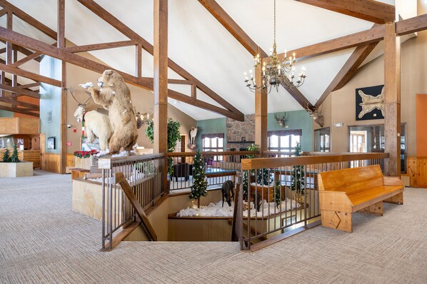 A spacious lobby with high ceilings, wooden beams, a chandelier, a wooden bench, and a Christmas tree. - Condo w/ Lock Off Near Granby Ranch, Golf, Fishing (Granby)