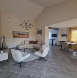 Un salon moderne comprenant un canapé d’angle, une table basse et un coin repas avec une table et des chaises.