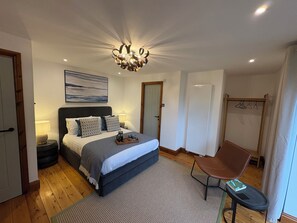 A bedroom with a bed, bedside lamps, a chandelier, a painting, a radiator, and a chair. - Lake District Windermere Retreat with Lake Views (Windermere)