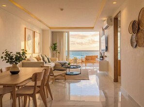 A modern living room with a sofa, dining table, and chairs, a balcony with a view of the sea, and a large window. - ¡Apartamento de lujo frente al mar en Mazatlán! (Mazatlan)