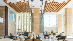 Eine moderne Lobby mit hoher Decke, Holzlamellen und Glaswänden.