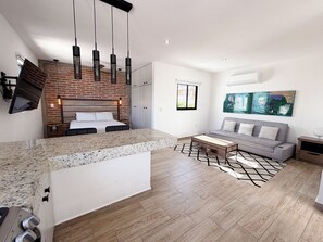 Un salon moderne avec un canapé, une table basse et un téléviseur fixé au mur, qui est en briques.