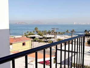 A balcony with a view of the sea, buildings, and a distant city skyline. - Stylish Loft a Short Walk to Malecon and Olas Altas (Mazatlan)