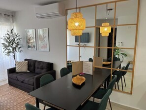 Ein modernes Wohnzimmer mit einer Couch, einem Esstisch, Stühlen und einem großen Spiegel.