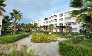 A hotel with a central courtyard, palm trees, and a white building with multiple balconies. - Departamento vacacional o de trabajo, 6 guest (Mazatlan)