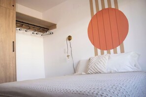 Ein Schlafzimmer mit einem Bett, einem Kleiderschrank, einer Wandleuchte und einem großen, runden Wandbild.