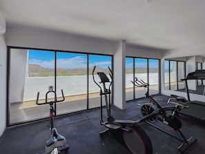 Un gimnasio con equipo de ejercicio y ventanas amplias que ofrecen vistas a un paisaje desértico.