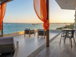 A terrace with wicker furniture, a view of the sea, and a sunset. - Stunning Ocean View Apartment with Private Terrace (Mazatlan)
