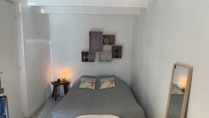 Ein Schlafzimmer mit Bett, Nachttisch, Lampe, Wandregalen und einem Spiegel.
