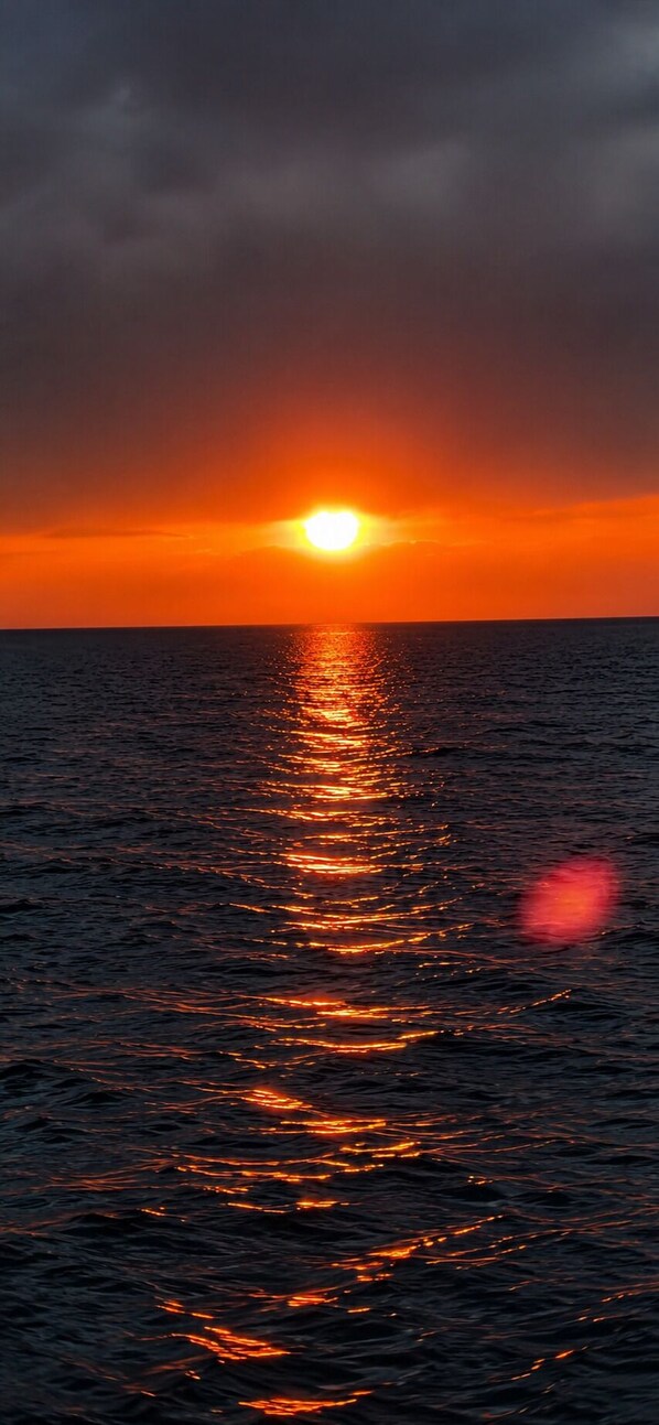 A sunset over the ocean with sunlight reflecting on the water. - Maksathouse (Tosor)