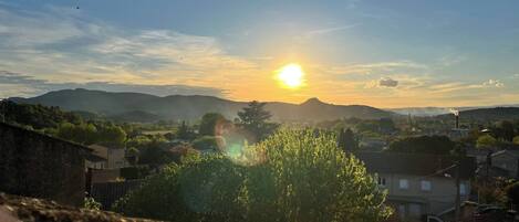 A rural landscape with a sunset, mountains, and scattered buildings.