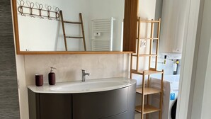A bathroom with a large mirror, a dark vanity, a wooden ladder, and a washing machine. - Grandpa Louis's Attic • 96 m² • Terrace • Vallon Pont D'Arc Center (Vallon-Pont-d'Arc)