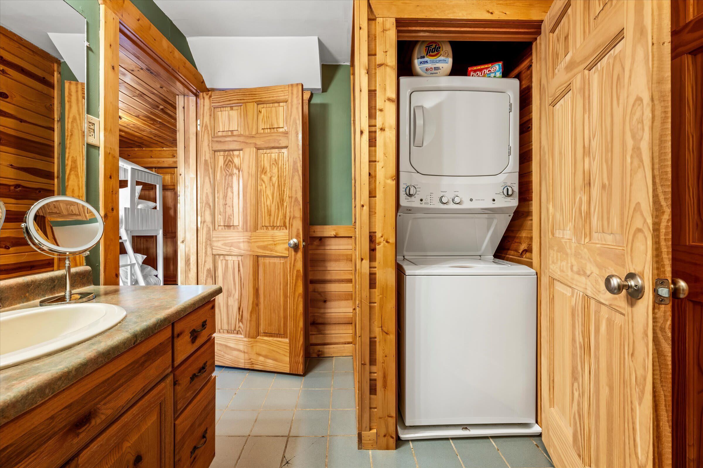 A compact bathroom with wooden cabinetry, a built-in washing machine, and a mirror.