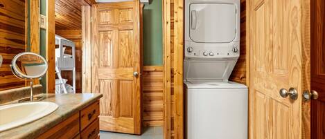 A compact bathroom with wooden cabinetry, a built-in washing machine, and a mirror.