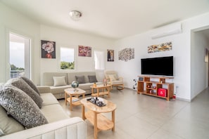 A modern living room with a sofa, coffee table, TV stand, and artwork on the walls.