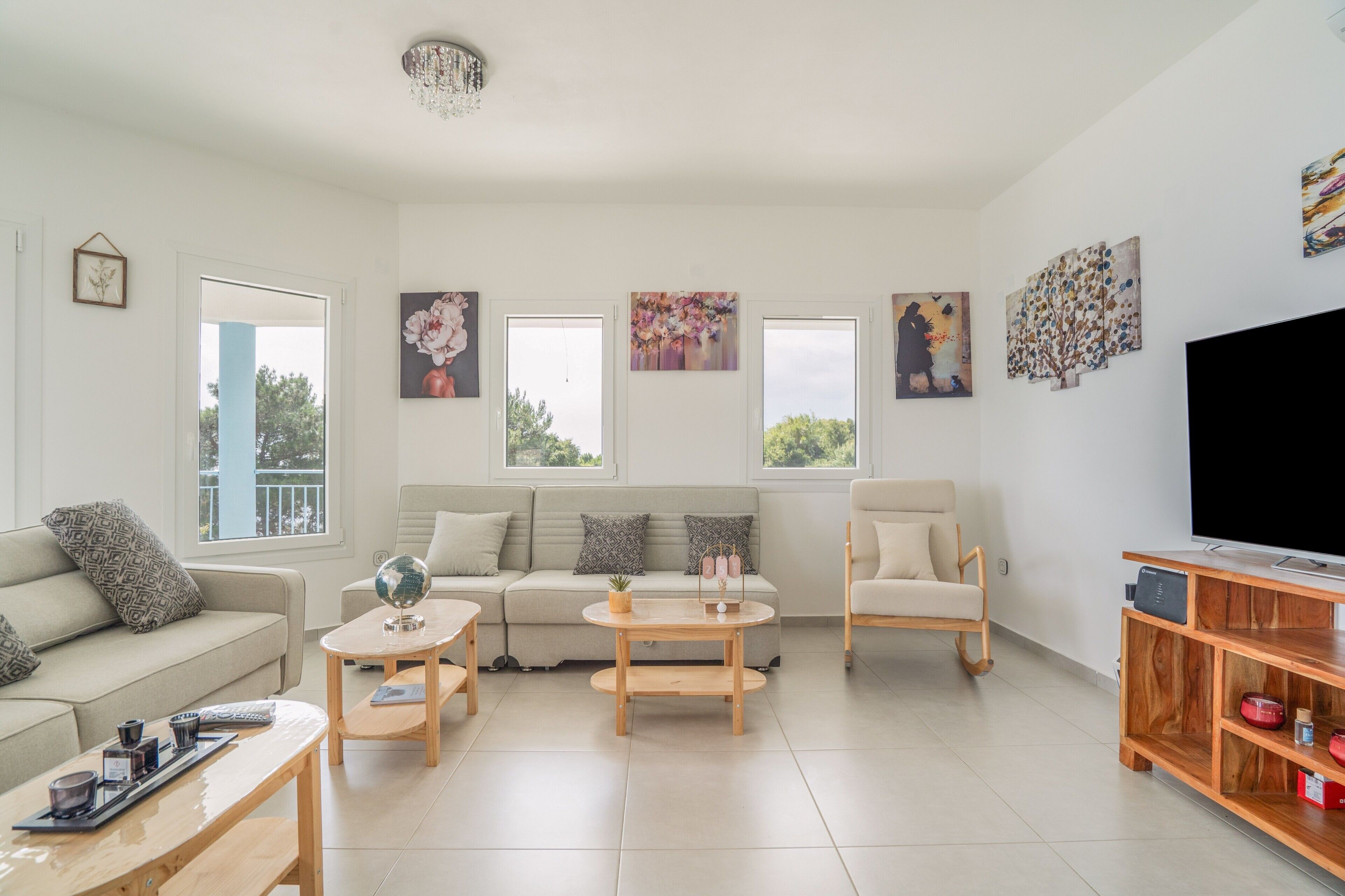 A living room with a sofa, coffee table, TV stand, and artwork on the walls.
