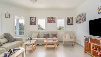 A living room with a sofa, coffee table, TV stand, and artwork on the walls.