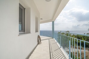 Un balcón con vista al mar, una ventana y una barandilla azul.