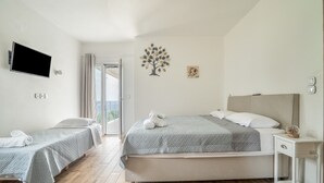 Hotellihuone, jossa on kaksi sänkyä, televisio, pieni pöytä ja ikkuna, jossa on verhot.