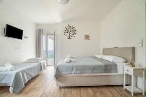 Ett hotellrum med två sängar, en tv, ett litet bord och ett fönster med gardiner.