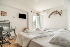 Un dormitorio con cama, escritorio, silla, televisión y ventana.