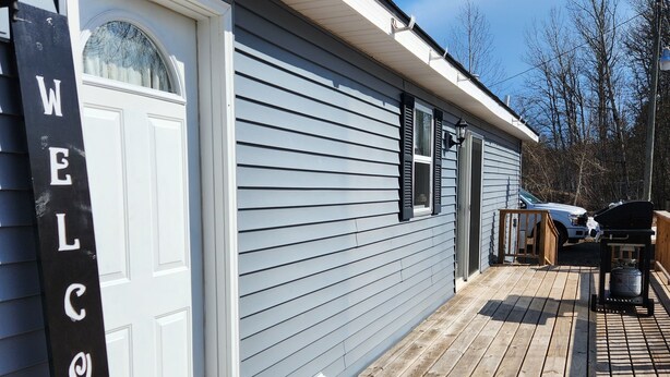 Una casa con un cartello 'WELCOME', un portone garage e un patio in legno.