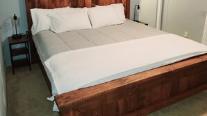 Una camera da letto con un letto in legno, un comodino, una lampada e una porta.