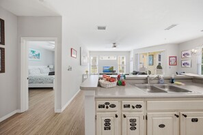 Eine moderne Küche mit einer zentralen Kochinsel, eingebauten Schränken und Blick in das angrenzende Schlafzimmer.