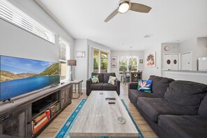 Ein Wohnzimmer mit Flachbildfernseher, einer Couch, einem Couchtisch und einem Bücherregal.